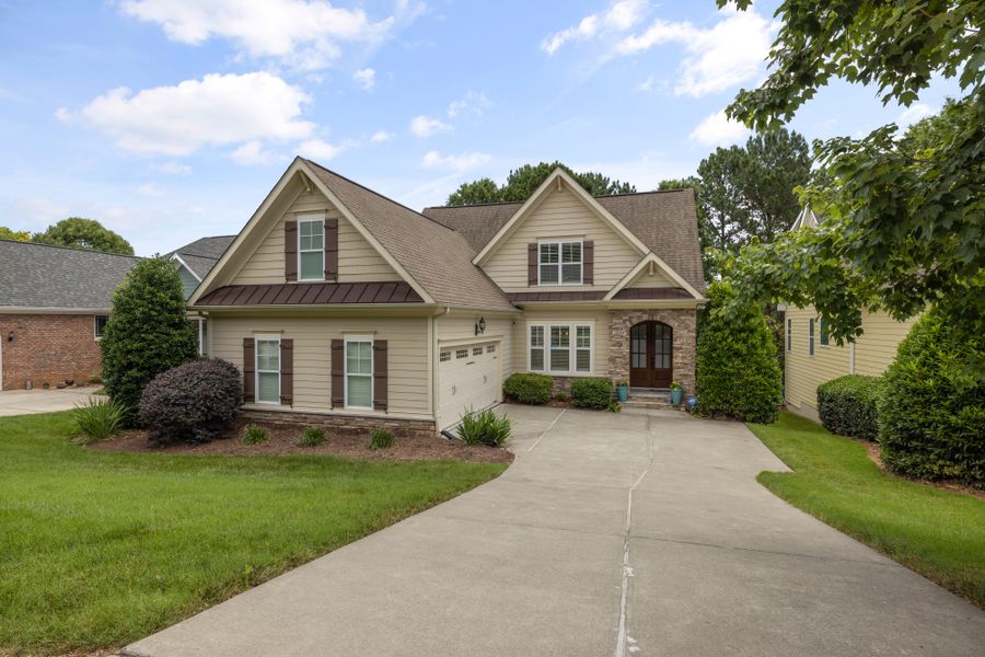 A brick and siding family home with a landscaped front lawn